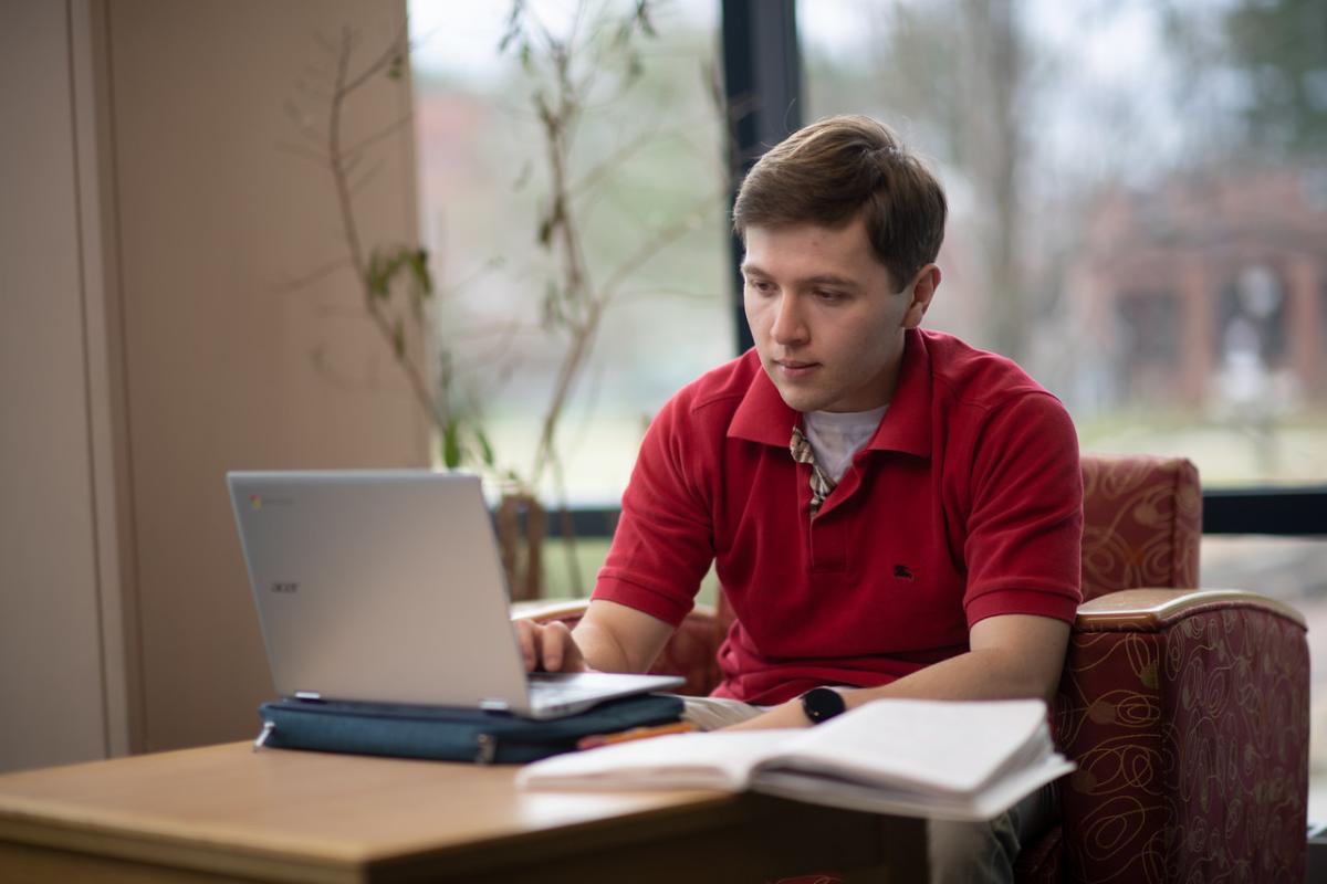 Graduate student sitting in the library with a laptop.