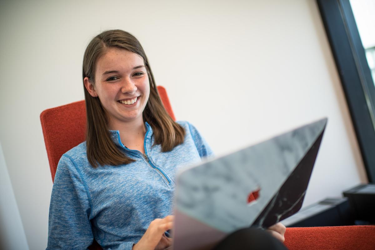 Student smiling while working on a laptop.