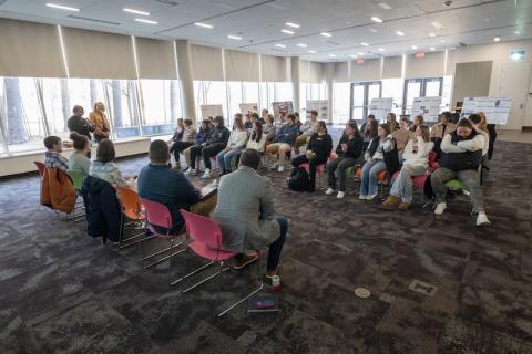 A crowd of students sitting on opposite sides of the room in rows, as part of Discover's Westfield's Shark Tank event.