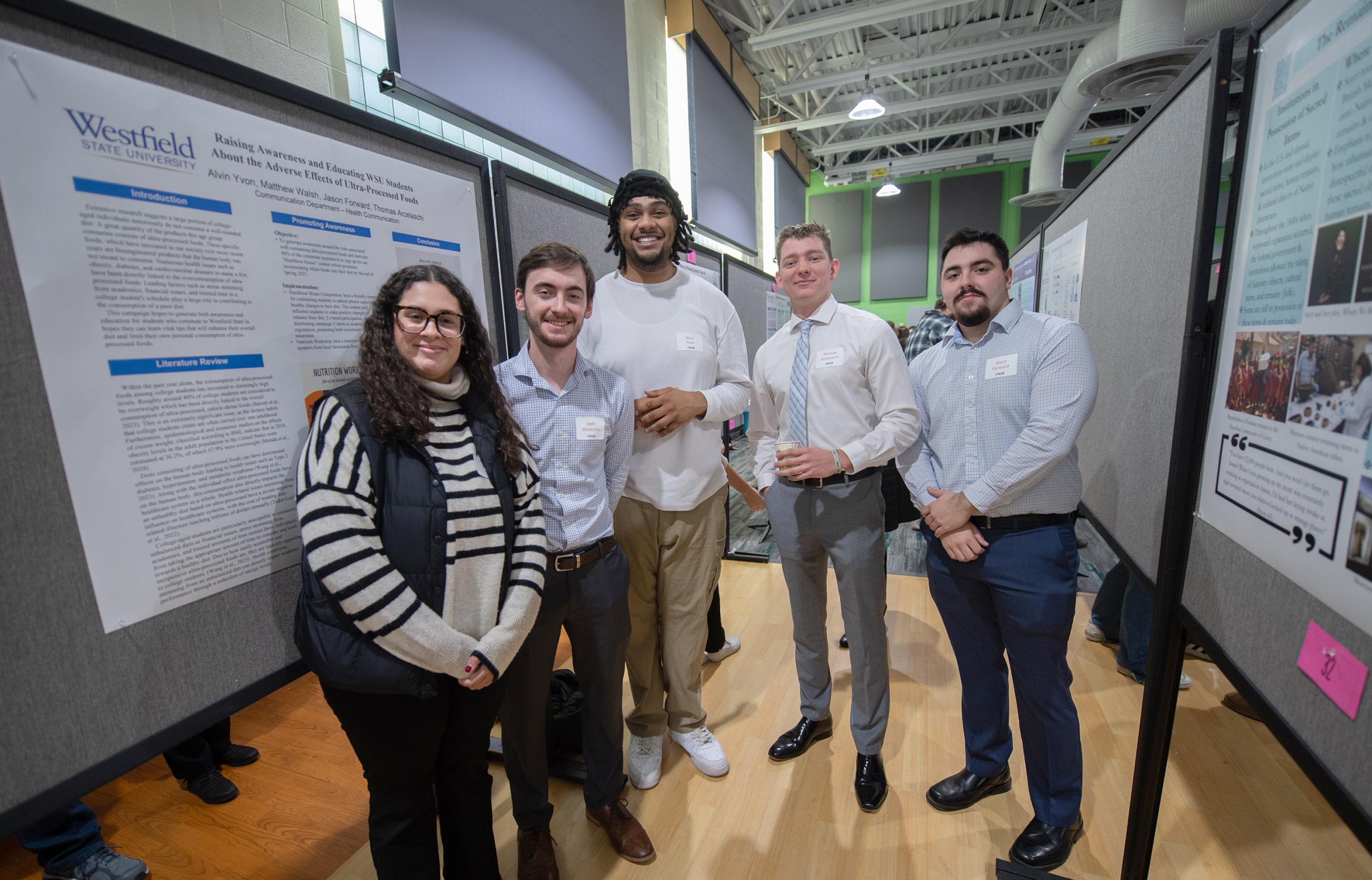 5 WSU students look toward the camera with their CURCA presentation boards behind them