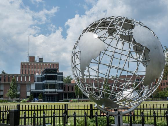 The globe sculpture on the campus green with the Ely Campus Center in the background