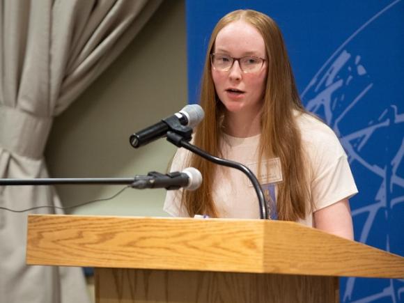 Political science student speaking at a podium during a campus event.