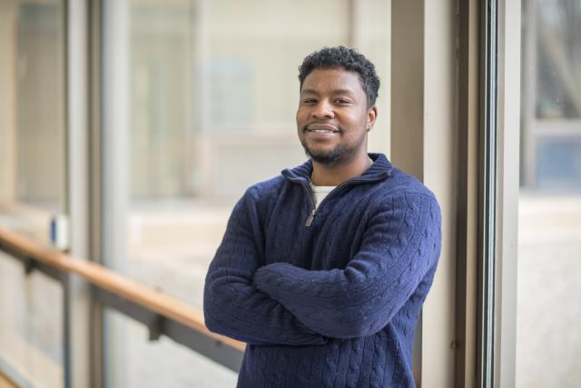 Male student in blue sweatshirt smiling at camera