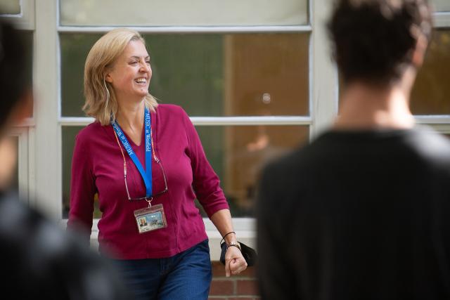 Music faculty member Mary Brown Bonacci wearing pink shirt smiling at students.