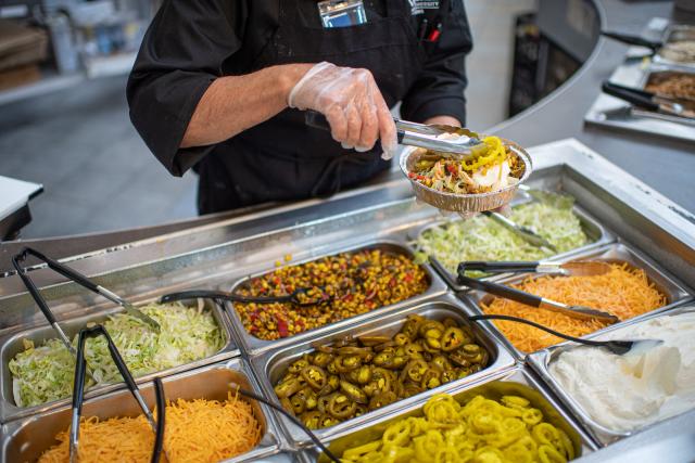 Dining services Mexican food station featuring lettuce, cheese, jalapenos, sour cream, and meat. 