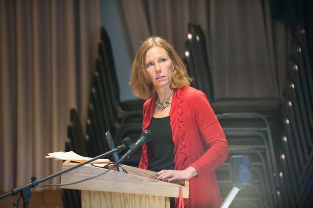 Management faculty member wearing red shirt with shoulder length red hair.