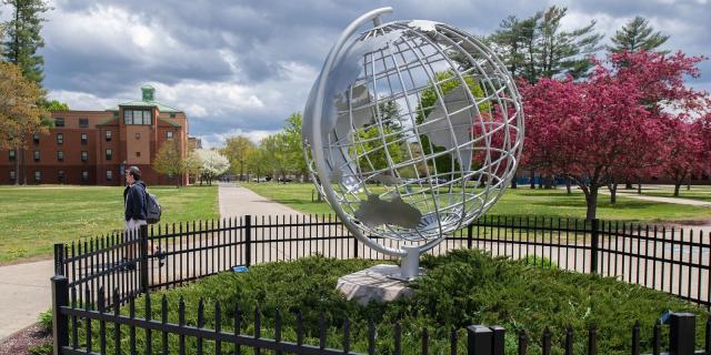 Globe in the spring with flowering trees behind it.