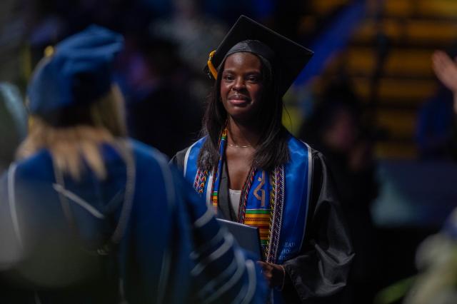 Student in cap and gown celebrating Political Science degree at commencement ceremony.