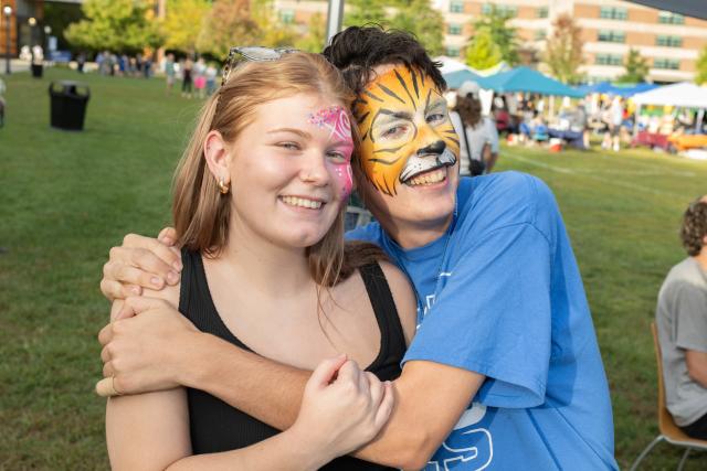 Two students smiling with their faces painted during Family Weekend.