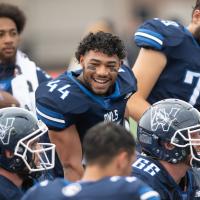 Westfield State footballs player smiles at his teammates on the sidelines during a game